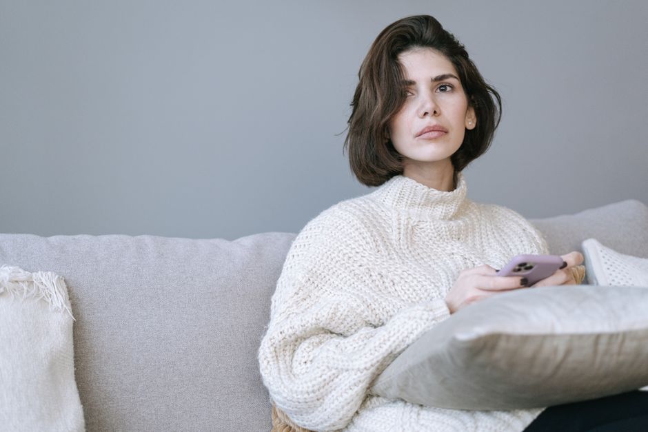 複雑な表情でスマートフォンを見つめる女性
