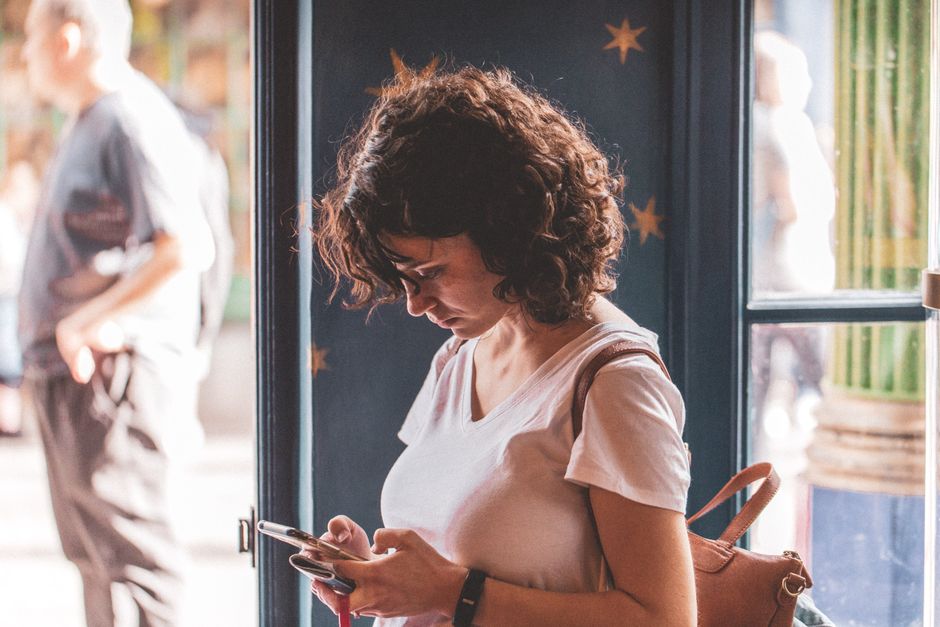 連絡しようか迷いながらスマートフォンを見る女性
