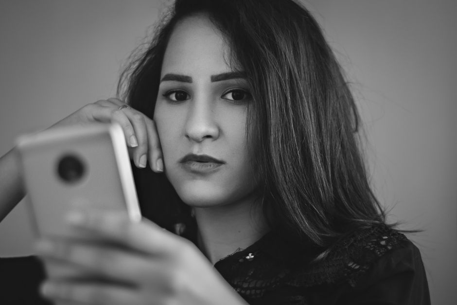 スマホを見つめ悩みながら先生を選ぶ女性