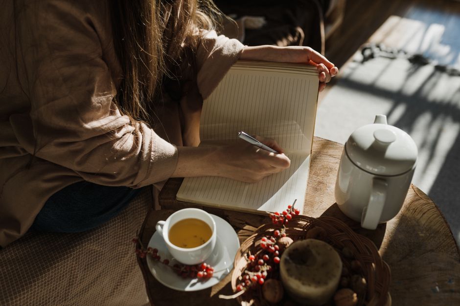 温かい紅茶とともにノートに書き込む女性の手元