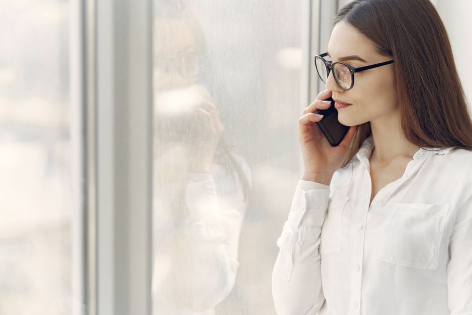 スマートフォンを見ながら考え込む女性