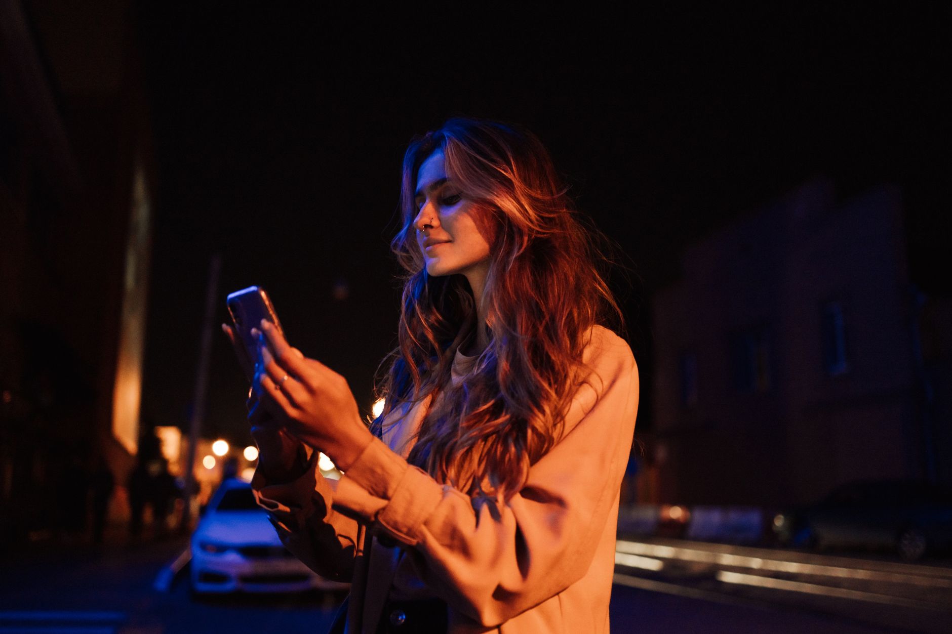 夜にひとりでスマートフォンを見つめる女性