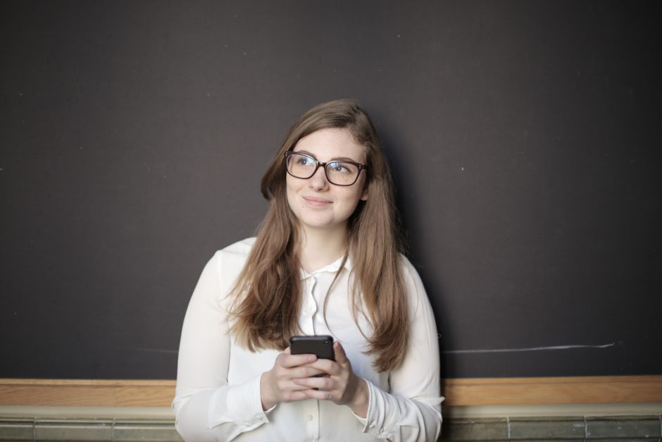 スマートフォンを見ながら考え込む女性